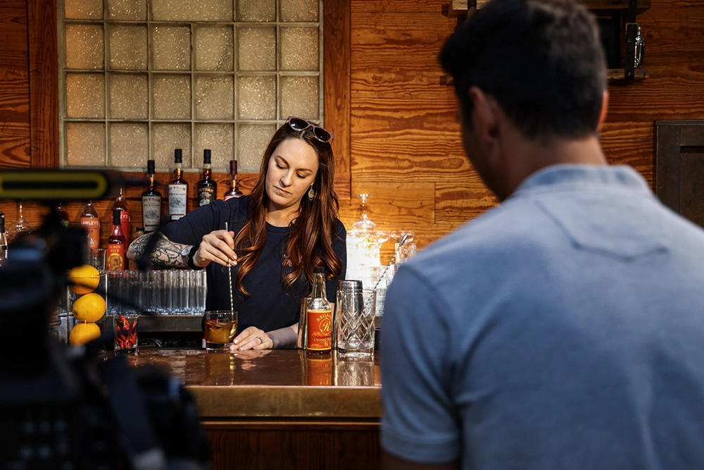 photographer from behind shooting bartender making a cocktail